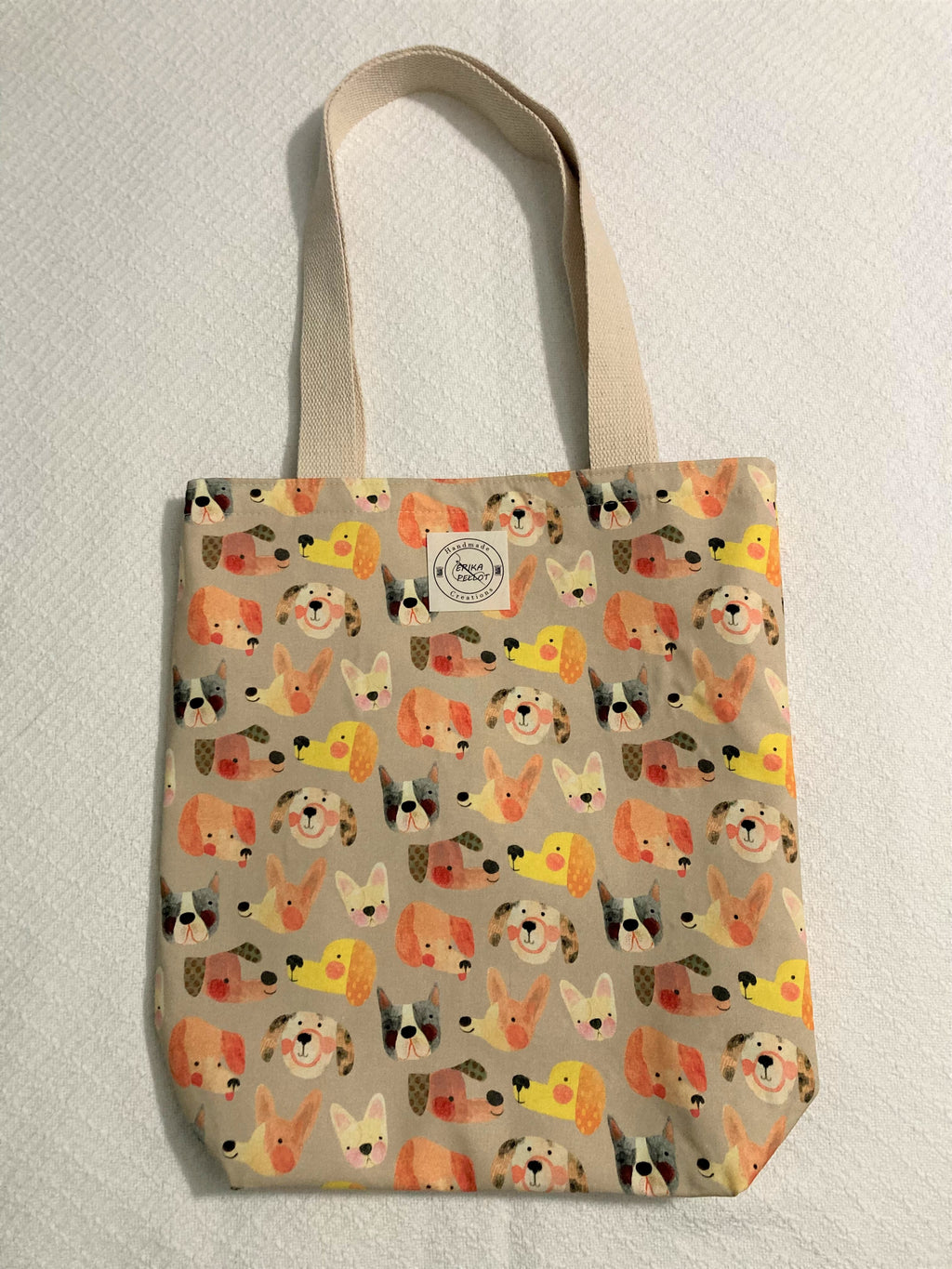 Look stylish while carrying around your stuff with our totally sustainable tote bag! Crafted from 100% cotton and adorned with happy dogs, it'll be sure to turn heads. So make the sustainable choice and grab one of these cuties today!  All the materials are 100% cotton making it a sustainable item. This cute handmade tote bag is around 15 inches wide and 18 inches long with a 4 inch bottom.