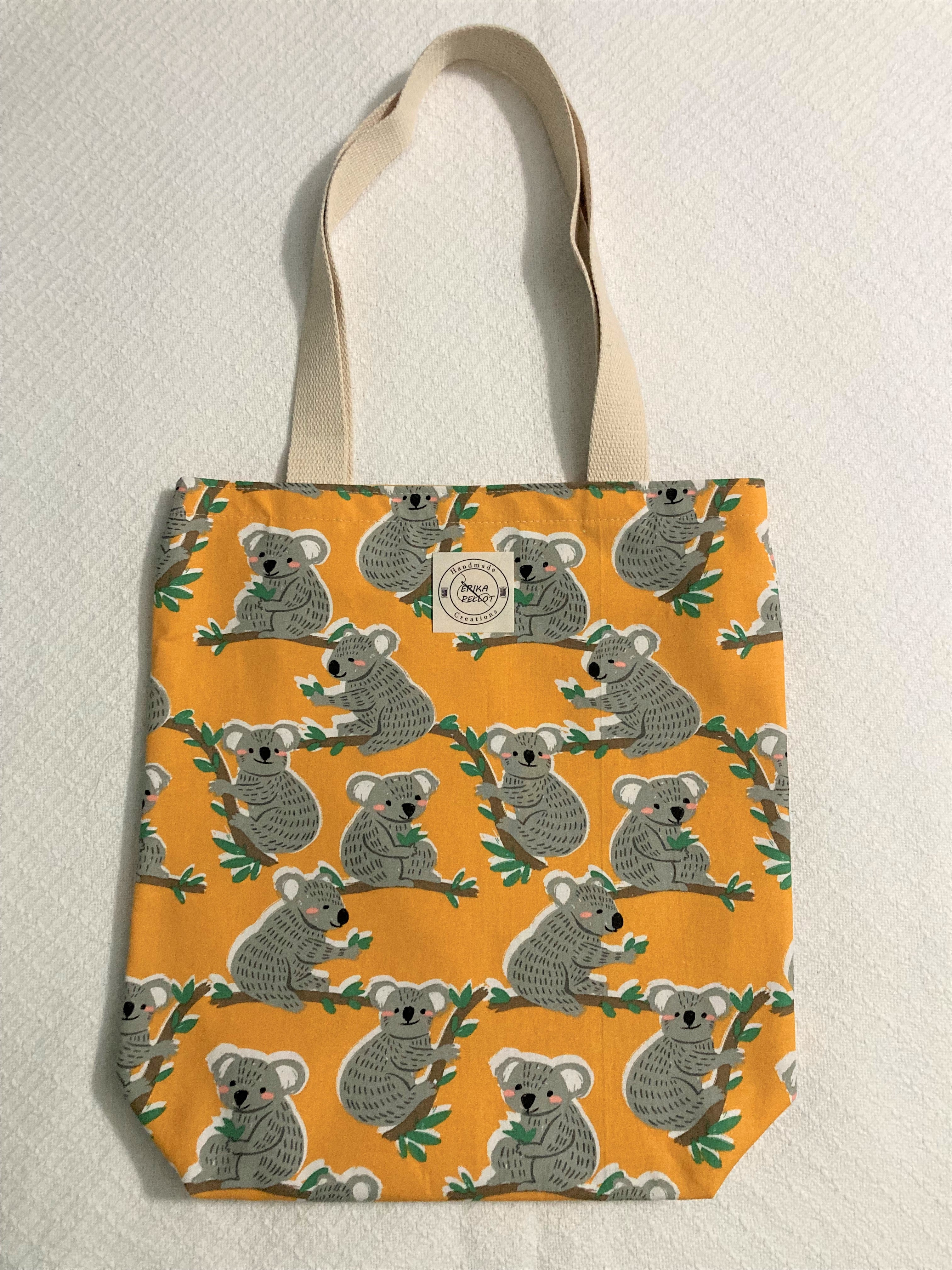 Show off your wild side with this adorable Happy Koala small tote! Crafted from 100% cotton, this bright bag features a cool design of happy koalas, trees, and warmth that'll have you feeling like you can take on anything - with cute style!  All the materials are 100% cotton making it a sustainable item. This cute handmade tote bag is around 15 inches wide and 18 inches long with a 4 inch bottom.