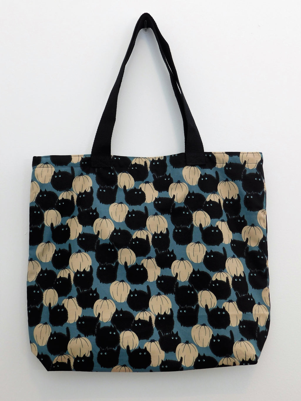 Cute black fluffy cats with pumpkins in a blue background. Handmade tote bag. Fabric, muslin lining, trim, and thread are all 100% cotton. Perfect for trick-or-treating, sporting through the Halloween season, or gift it to a teacher or friend just because its a cute tote bag!  Machine wash gentle warm, non-chlorine bleach, tumble dry low and warm iron. Measurements are around 16in x 19in x 4in.  