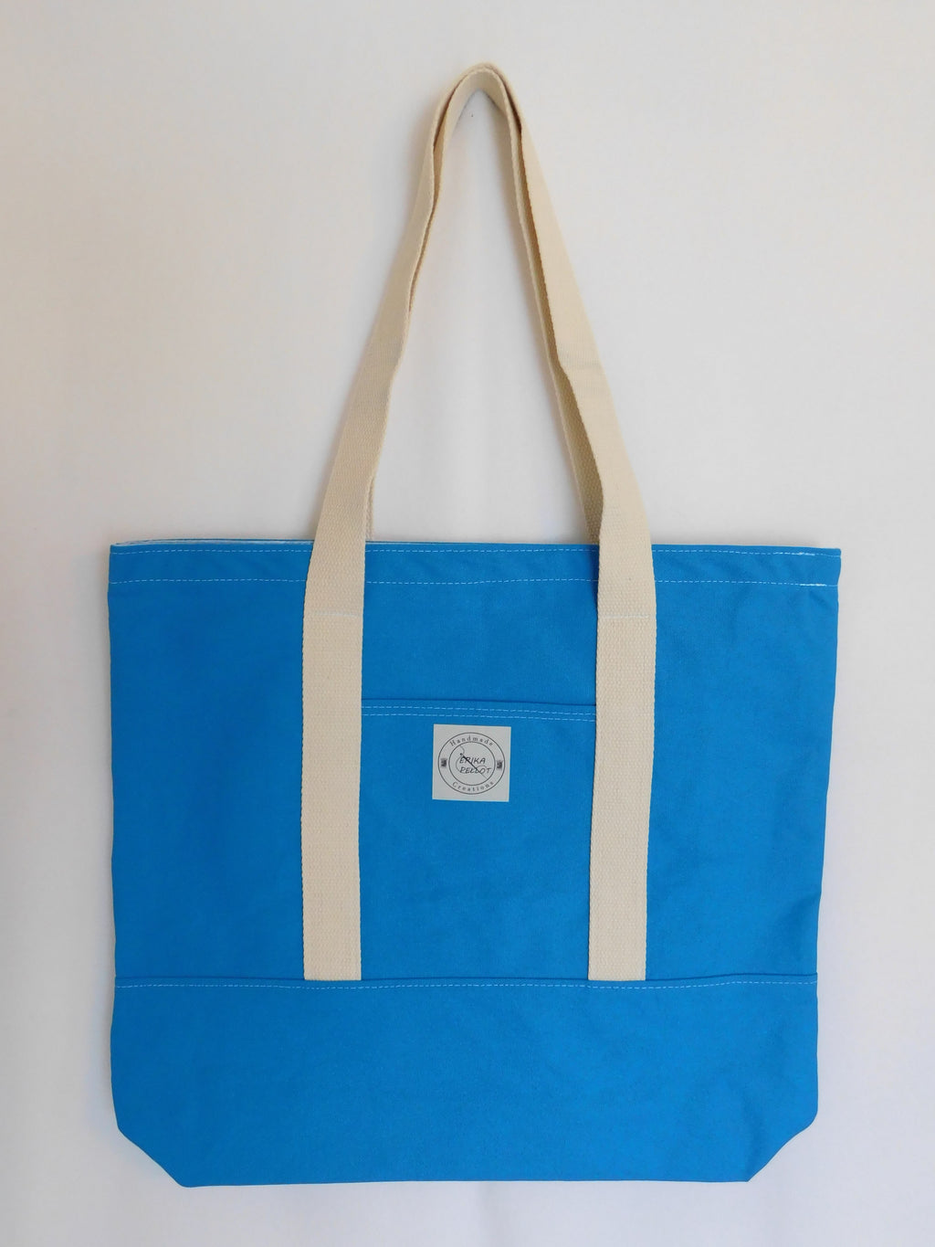 This big solid blue handmade tote bag is very spacious and really sturdy.  There is a slip pocket on the outside measuring around 8x8. The longer straps adds sturdiness to the cotton canvas tote. The inside is lined with a light blue fabric and SF 101. This tote also has a slip pocket inside big enough to fit your phone, keys and a wallet.  All the materials; canvas, lining, thread, and trim are 100% cotton.  Measurements are around 16in x 19in x 4in.