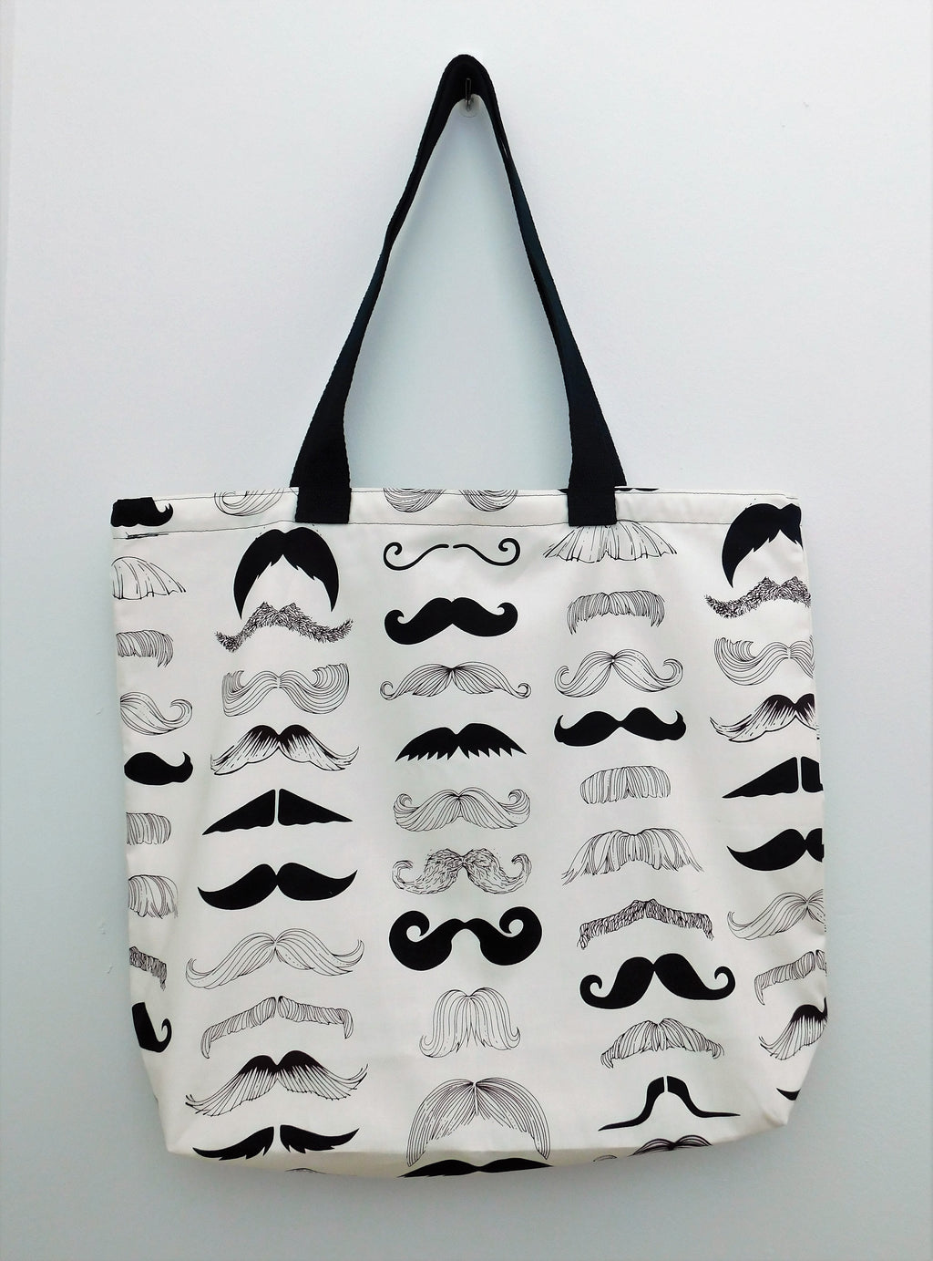 This mustache handmade tote bag is fun! This bag has different types of mustaches. They are black in color with a white background. The tote has black trim and is lined with muslin fabric. All materials are 100% cotton. Measurements are around 16in x 19in x 4in.