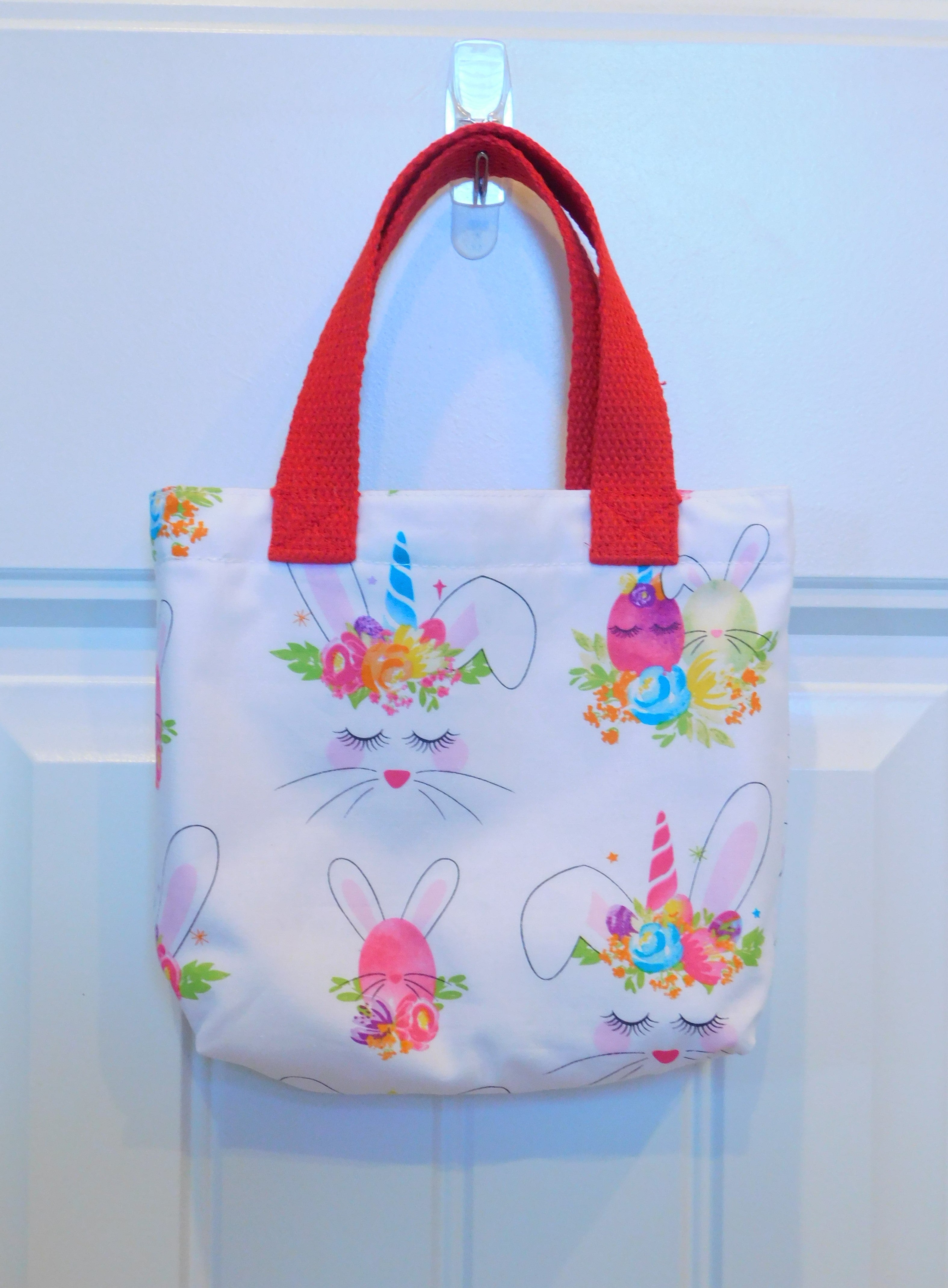 Let's mix a bunny and a unicorn! This cute handmade mini tote bag is perfect for your little one to style with new Easter outfits. The mini tote has white bunnies, yellow, pink, purple, and blue crown flowers. All in a white background. All the materials from fabric, muslin lining, thread and trim are 100% cotton. To care for your mini tote machine wash warm, tumble dry low, cool iron, non-chlorine bleach. Measurements are around 9in x 7in x 2in.