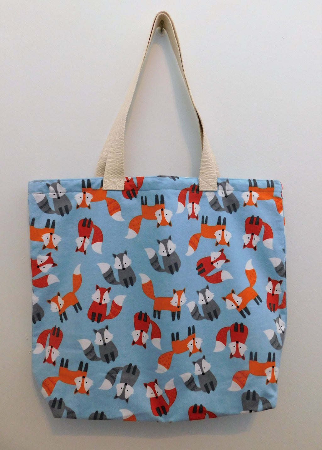 Baby foxes in blue! Beautiful light blue handmade tote bag covered in gray, red, and orange baby foxes. The fabric is super snuggle making it extra soft. Muslin lining, thread and trim are also 100% cotton. To care for your tote machine wash gentle cold, non-chlorine bleach or fabric softener, tumble dry low, cool iron. Measurements are around 16in x 19in x 4in.