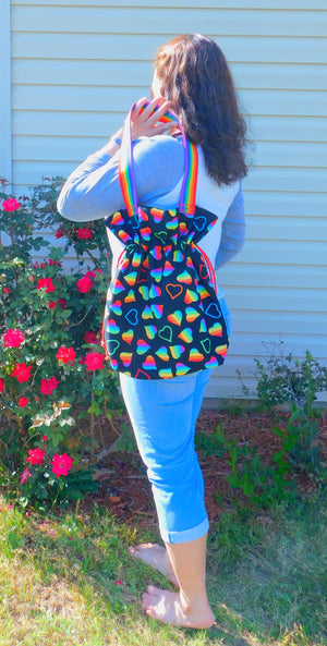 Happy Pride! This cute tote has lots of  LGBTQ+ rainbow hearts in a black background and it's just beautiful! The tote has a drawstring to secure your bag and the inside pocket is big enough to fit a cell phone and keys. Fabric, muslin lining, thread and are 100% cotton. The trim is 90% polypropylene and 10% polyester. To care for your tote machine wash gentle cold, tumble dry low, non-chlorine bleach and cool iron. Measurements are around 16in x 14 1/2in x 4in.