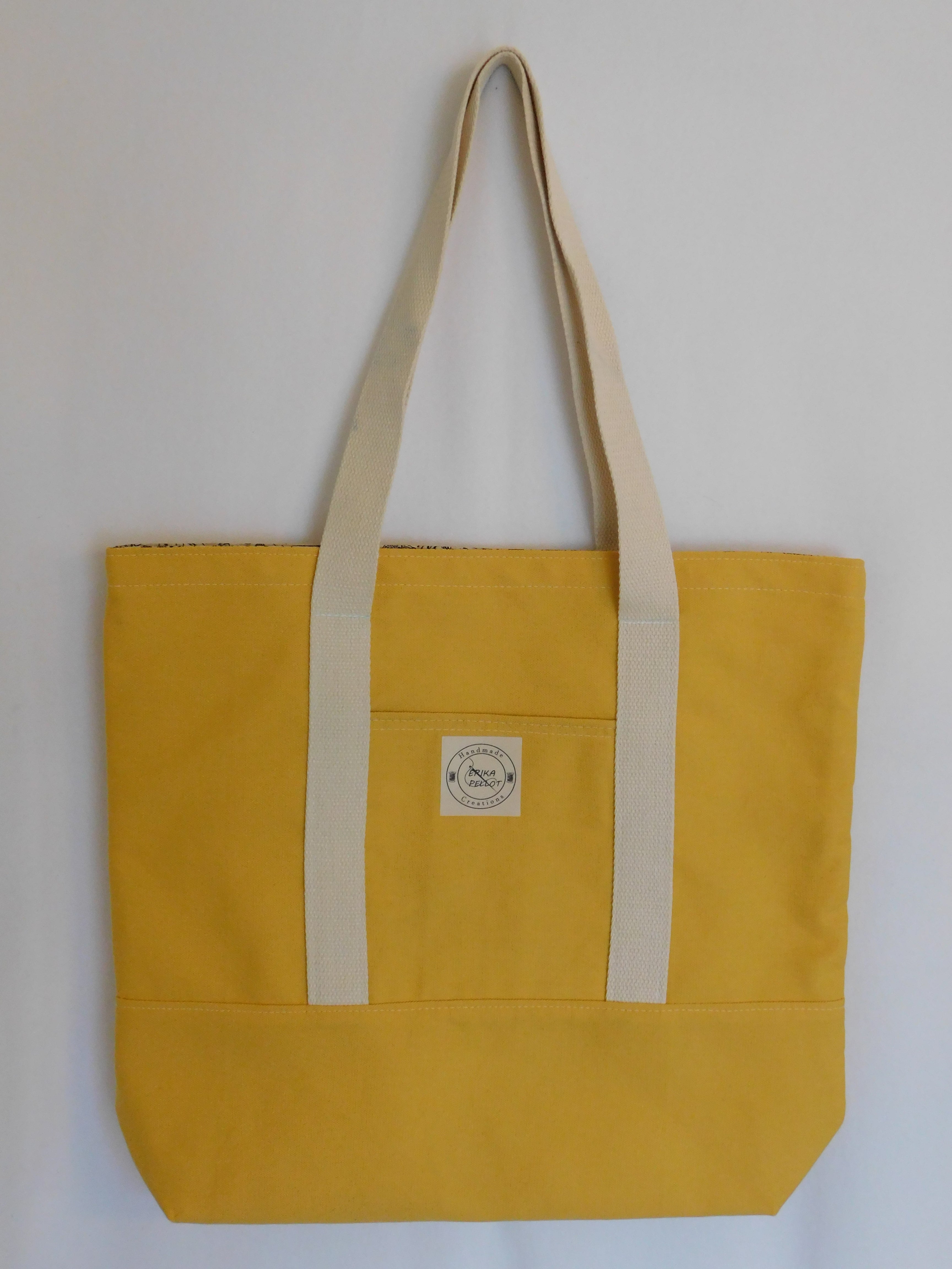 This solid mustard handmade tote bag is very spacious and really sturdy.  There is a slip pocket on the outside measuring around 8x8. The longer straps adds sturdiness to the tote. The inside is lined with a light brown fabric with bakery images such as loafs of bread and baking utensils. This tote also has a slip pocket inside big enough to fit your phone, keys and a wallet.  All the materials; fabric, lining, thread, and trim are 100% cotton.  Measurements are around 16in x 19in x 4in.