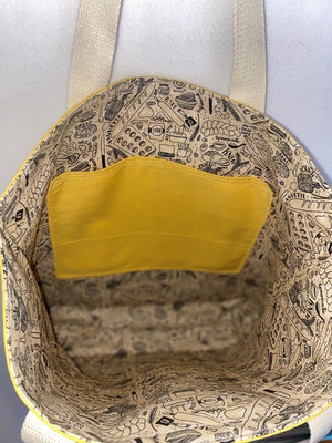 This solid mustard handmade tote bag is very spacious and really sturdy.  There is a slip pocket on the outside measuring around 8x8. The longer straps adds sturdiness to the tote. The inside is lined with a light brown fabric with bakery images such as loafs of bread and baking utensils. This tote also has a slip pocket inside big enough to fit your phone, keys and a wallet.  All the materials; fabric, lining, thread, and trim are 100% cotton.  Measurements are around 16in x 19in x 4in.