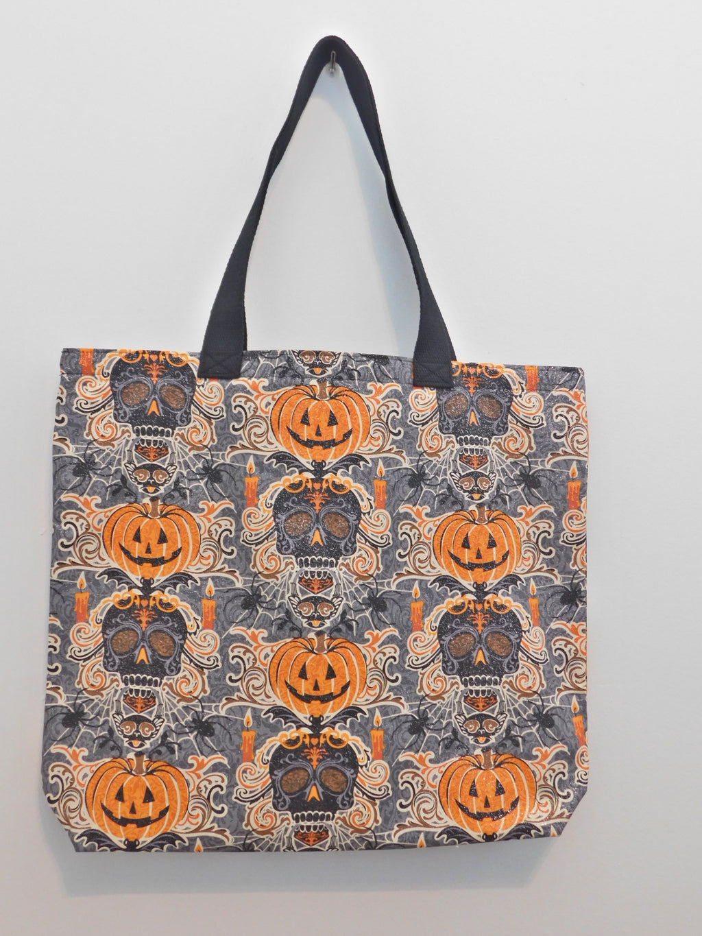 Oh, happy pumpkins and sugar skulls! This handmade Halloween tote bag has orange happy pumpkins, black sugar skulls with gray and orange design and a bat on top of the skull. The background is gray with cobwebs, candles and black spiders and it has glitter! The fabric, muslin lining, black trim, and thread are all 100% cotton. Machine wash gentle cold, non-chlorine bleach, tumble dry low, remove quickly, use a warm iron. Measurements are around 18in x 16in x 3in.