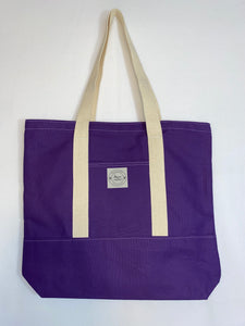 This solid purple handmade tote bag is very spacious and really sturdy.  There is a slip pocket on the outside measuring around 8x8. The longer straps adds sturdiness to the tote. The inside is lined with a light purple fabric with different specs of colors. This tote also has a slip pocket inside big enough to fit your phone, keys and a wallet.  All the materials; fabric, lining, thread, and trim are 100% cotton.  Measurements are around 16in x 19in x 4in.