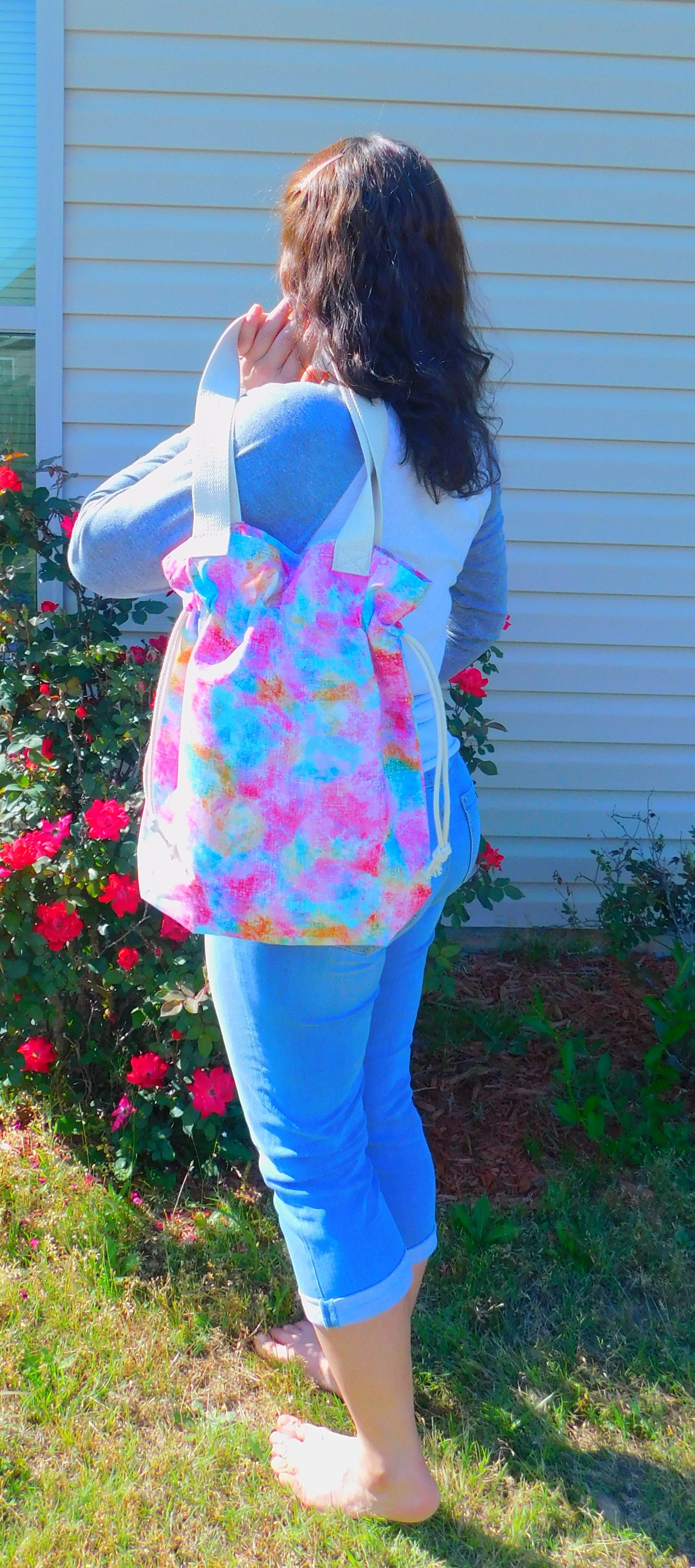 Beautiful colors! This cute tote has a rainbow of splashed colors with different shades of pink, blue,yellow and green. It's just adorable! It has a drawstring to secure your bag and the inside pocket is big enough to fit a cell phone and keys. Fabric, muslin lining, thread and trim are 100% cotton. To care for your tote machine wash warm, tumble dry low, remove promptly, no bleach and cool iron. Measurements are around 16in x 14 1/2in x 4in.