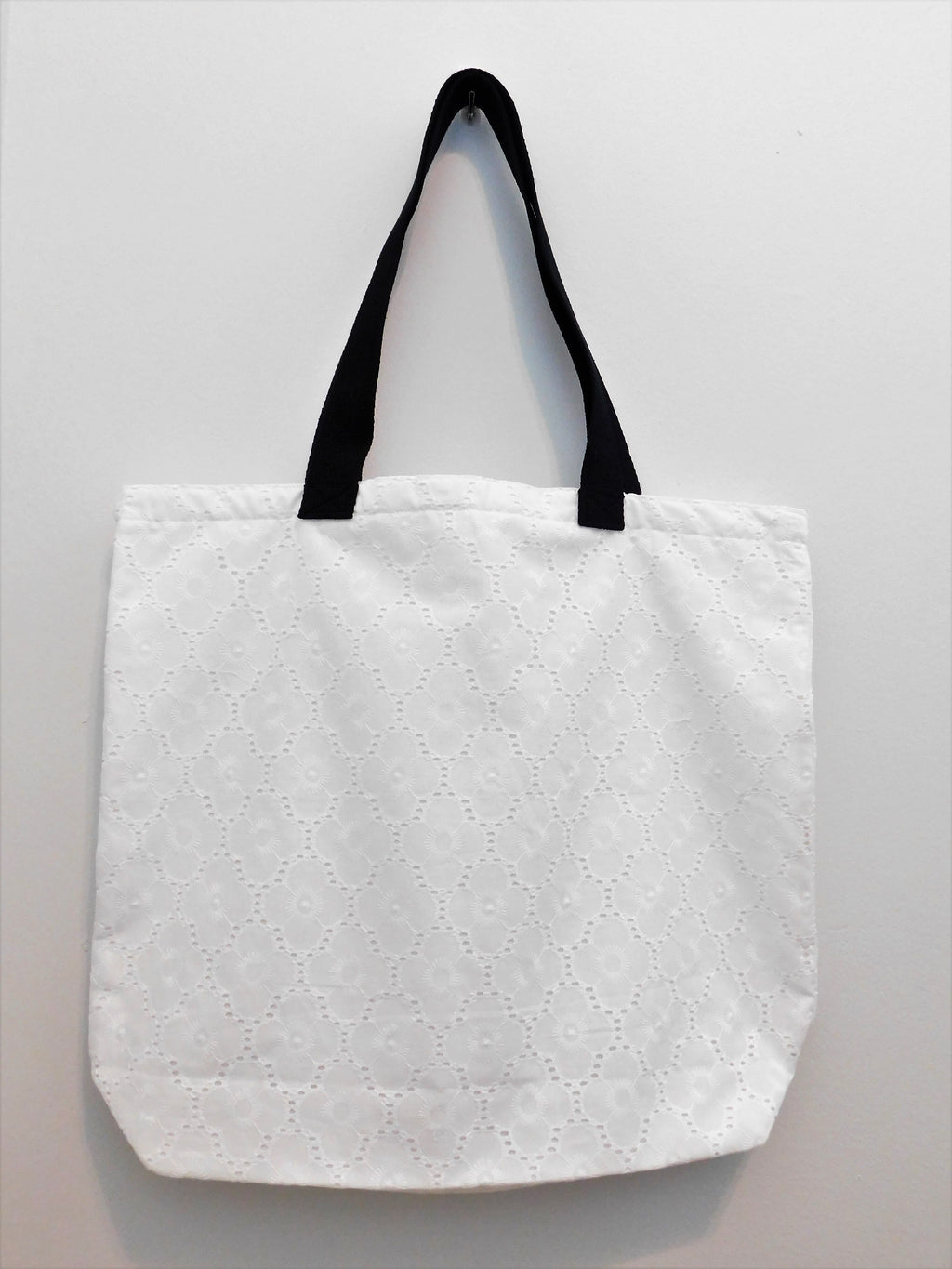 Elegance! This white floral eyelet handmade tote bag is perfect for spring. Fabric, muslin lining, black trim and thread are all 100% cotton. Machine wash cold, delicate cycle, tumble dry low. Measurements are around 19in x 16in x 4in.