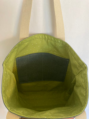 This solid green woven handmade tote bag is very spacious and really sturdy.  There is a slip pocket on the outside measuring around 8x8. The longer straps adds sturdiness to the tote. The inside is lined with a light green fabric with small sparse white dots. This tote also has a slip pocket inside big enough to fit your phone, keys and a wallet.  All the materials; fabric, lining, thread, and trim are 100% cotton.  Measurements are around 16in x 19in x 4in.