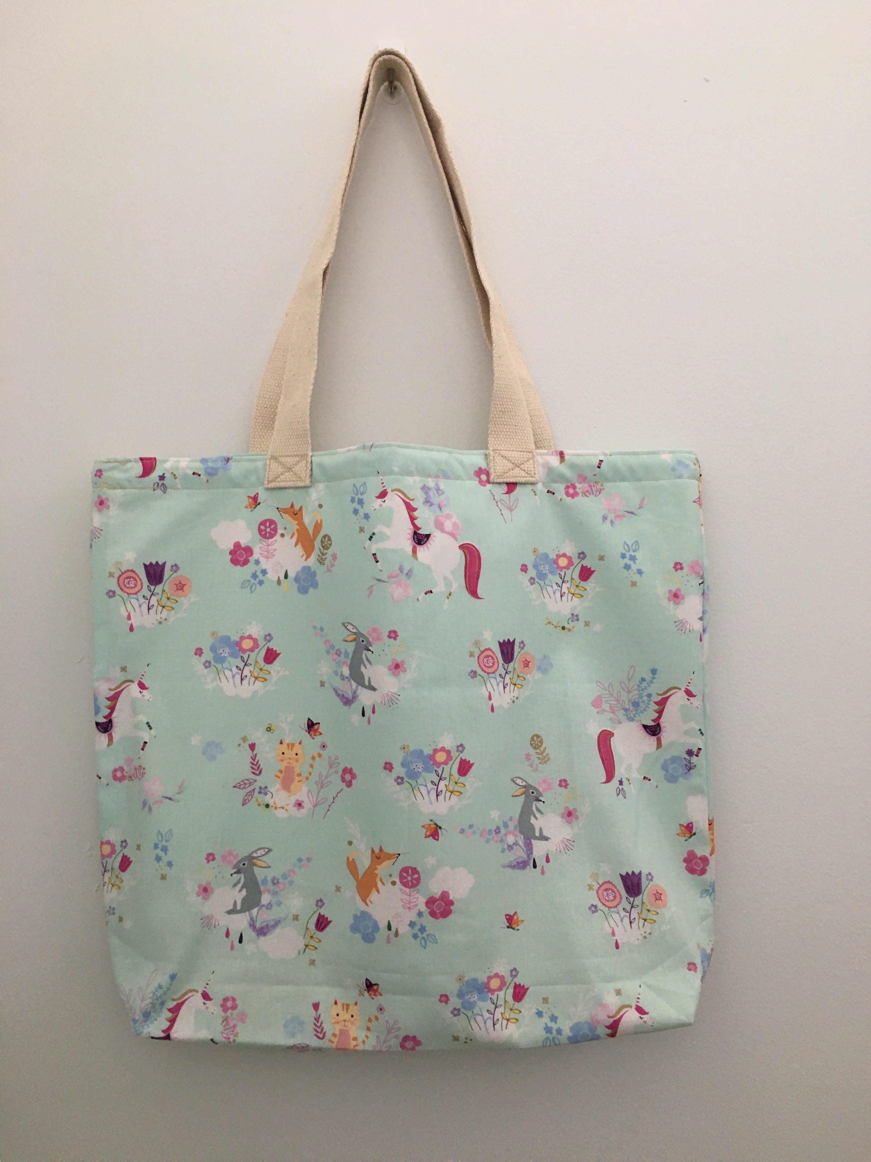 This is a magical world with unicorns and their forest friends. This mint-green handmade tote has white unicorns accompanied by foxes, rabbits, yellow cats, butterflies, and pink and blue flowers. All the fabric; from the muslin lining to the trim and the thread are 100% cotton. Measurements are around 16in x 19in x 4in.