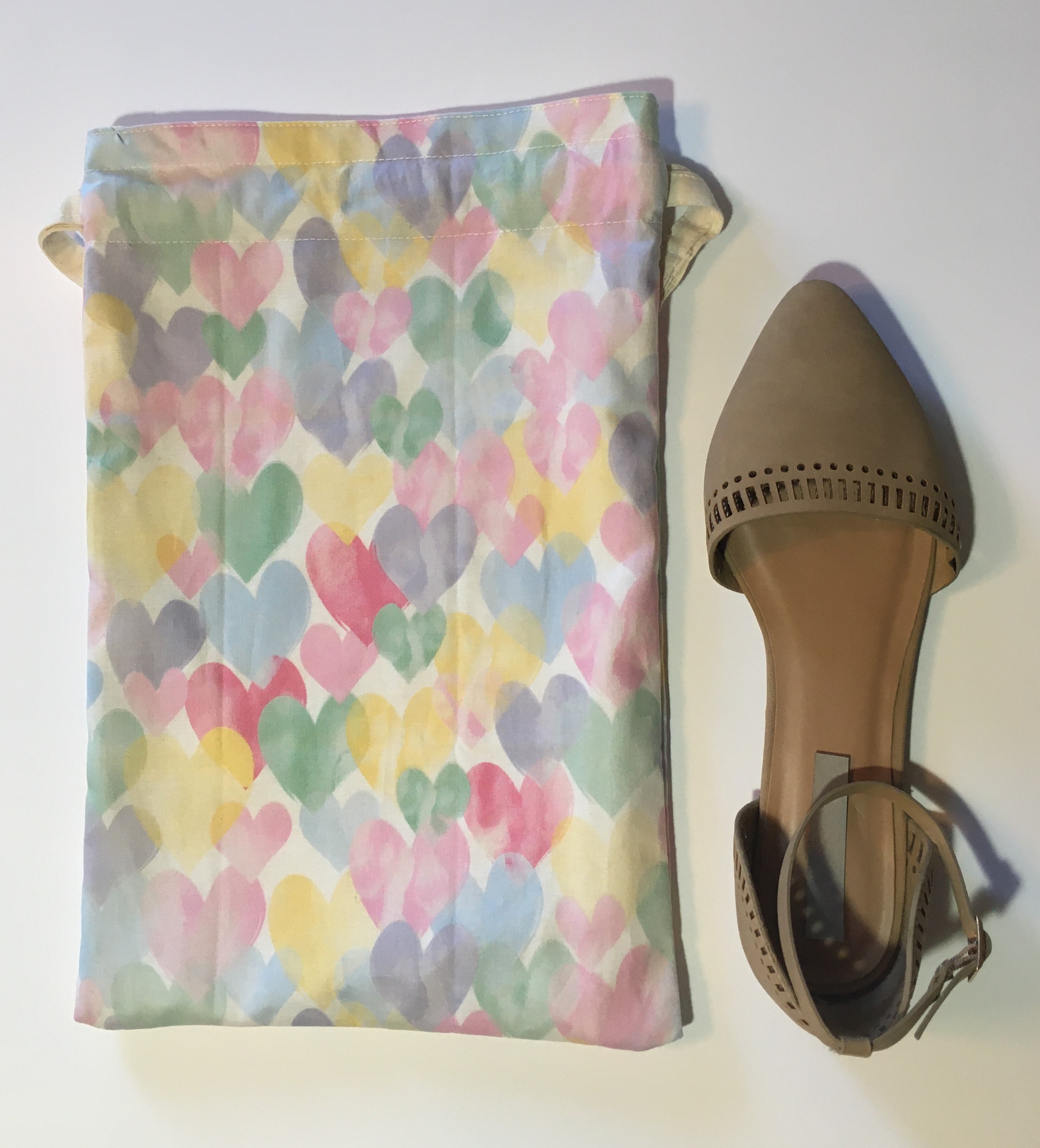 Lots of hearts! This beautiful handmade shoe / travel bag is 100% cotton and is also lined with muslin fabric. The travel bag has pastel red, blue, yellow, green and purple hearts in a white background and pull strings in the top to secure the content. This bag can be used for holding your shoes, underwear, socks, or just using it as a gift bag. Measurements are around 14in x 10in. (shoe not included)